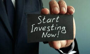 Businessman holding sign saying start investing now