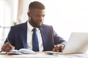 a man in a suit sitting at a desk with a laptop