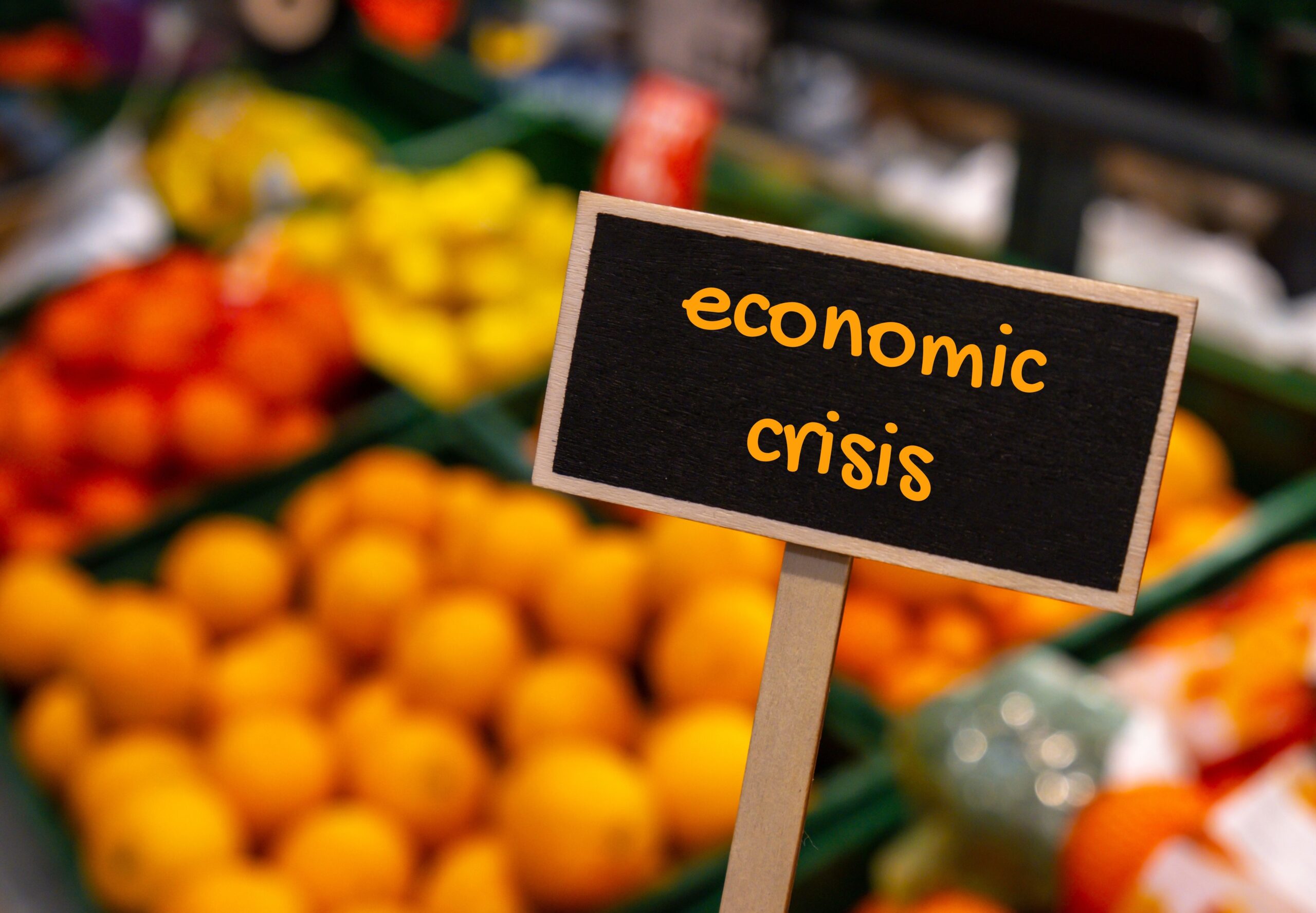 sign that says economic crisis in front of a collection of fruits