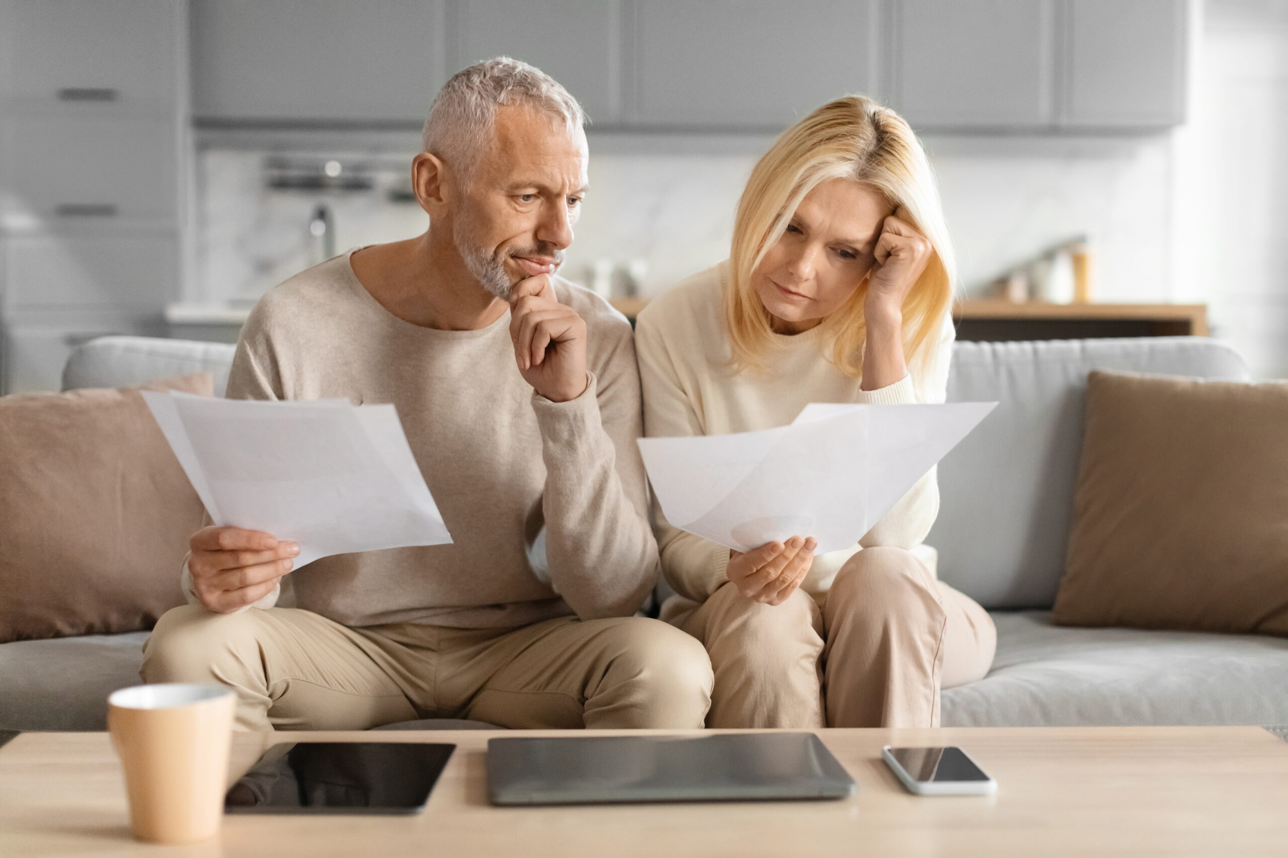 Concerned couple reviewing papers with serious faces