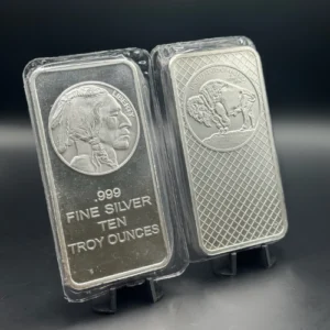 Two silver bars in plastic cases; left reads '.999 FINE SILVER TEN TROY OUNCES' with a Native American profile, right shows a buffalo on a patterned surface.