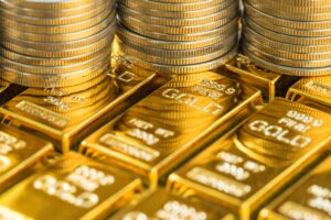 Close-up of stacked gold bars and shiny gold coins, highlighting wealth and precious metal bullion storage.