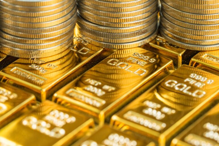 Close-up of stacked gold bars and shiny gold coins, highlighting wealth and precious metal bullion storage.