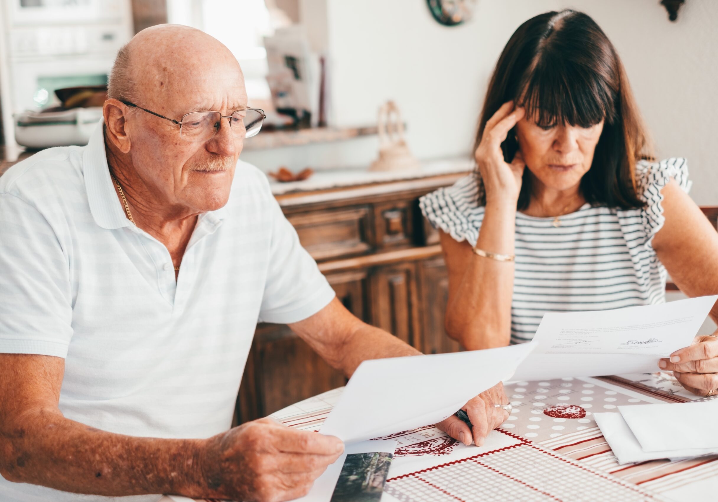 senior-couple-sitting-at-home-table-with-paper-doc-2024-11-02-23-37-31-utc